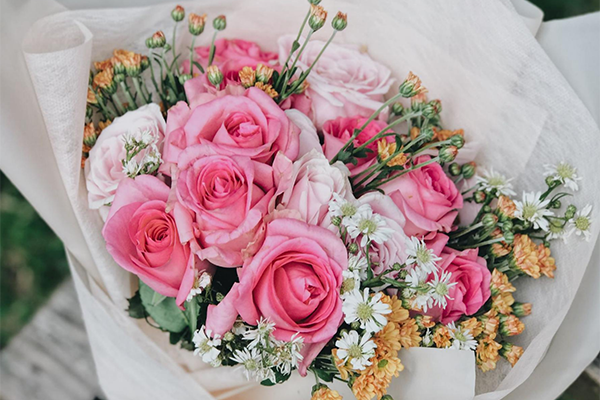 A bouquet of roses, with some white and yellow flowers mixed in.