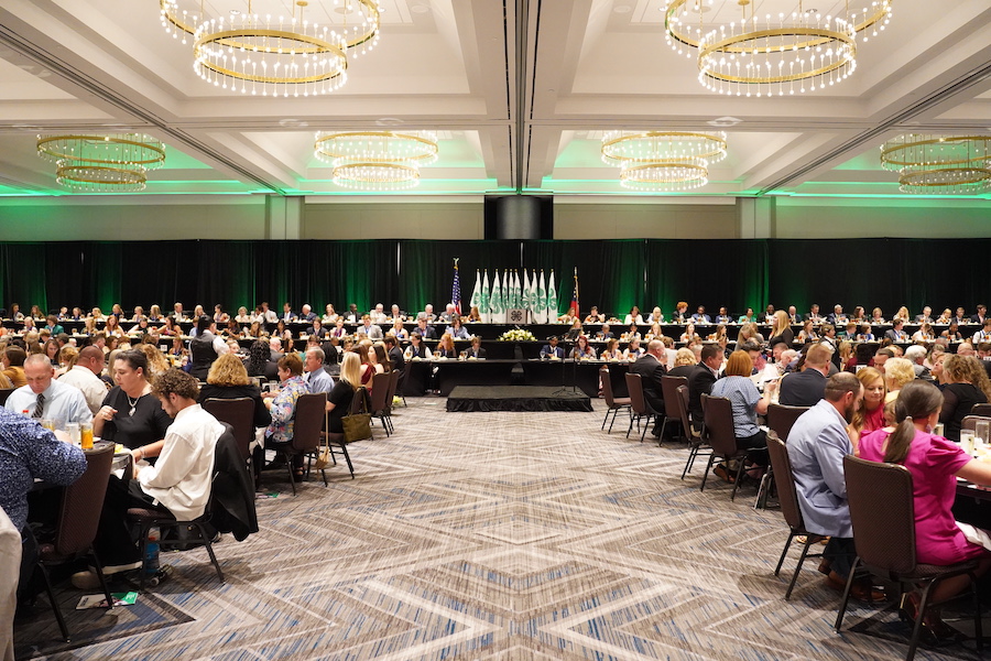 The Georgia 4-H State Congress event was held at Crowne Plaza at Ravinia in Atlanta, where the room is decorated with green lights, curtains, and 4-H flags surrounding tables of people.