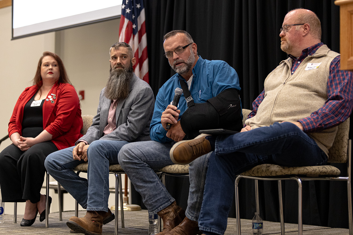 Four people sit in chairs on a stage for a panel discussion. 