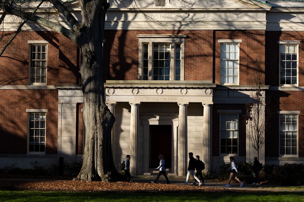 View of the front entrance of Hirsch Hall with students walking on the sidewalk in the foreground.