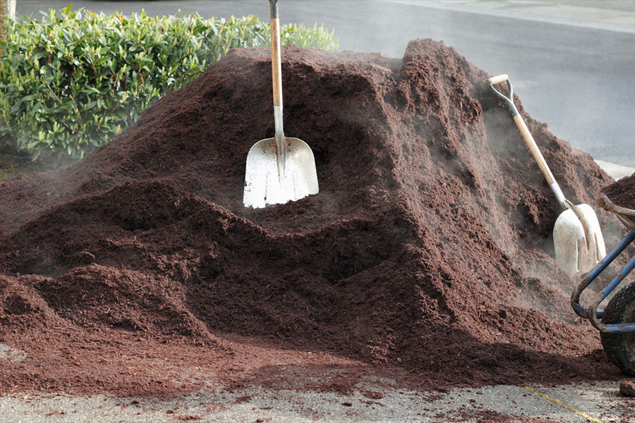 A steaming pile of soil sits on a drive with two shovels nearby