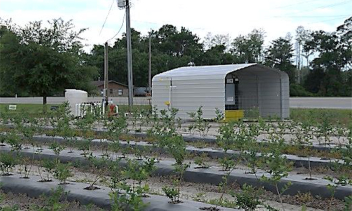 A metal shed with two sides covers irrigation equipment in a field