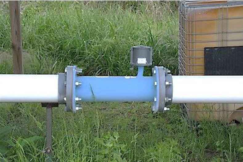 A blue flow meter is positioned with the meter above the pipe