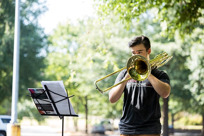 A male student plays a trombone outside
