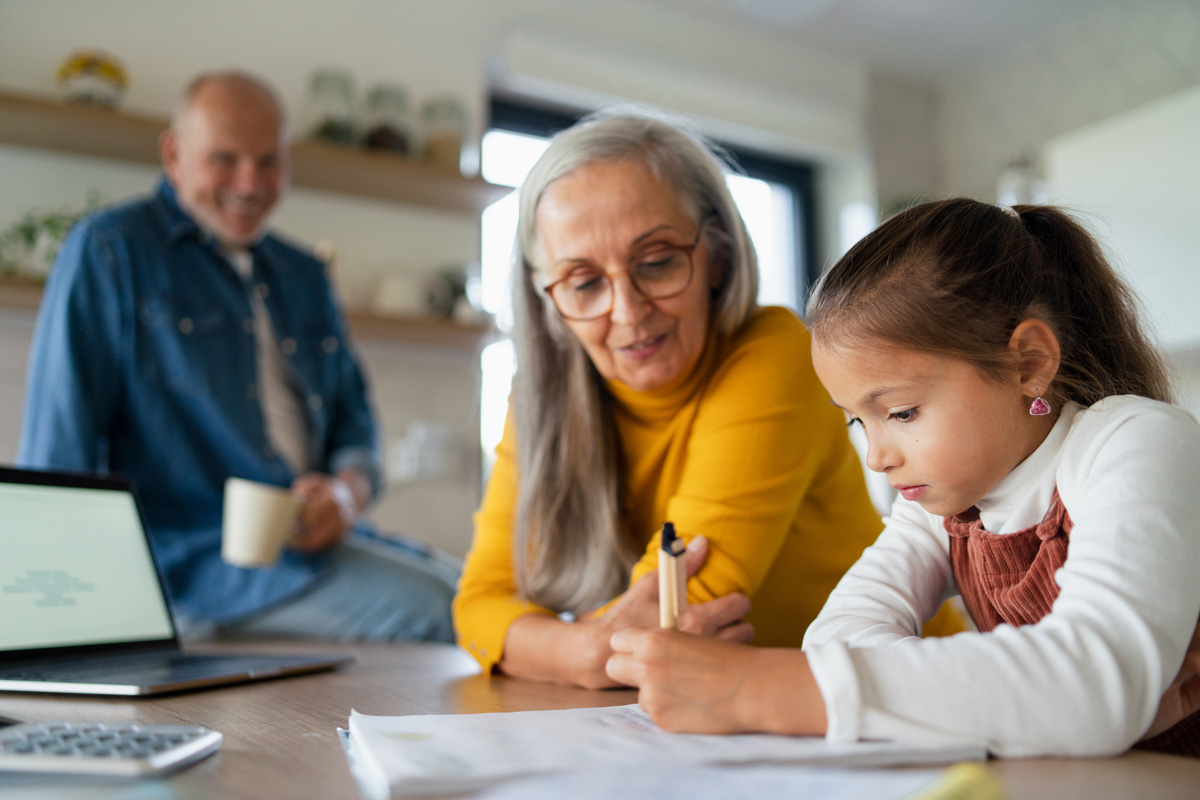 An older couple helps a child with their homework at a table