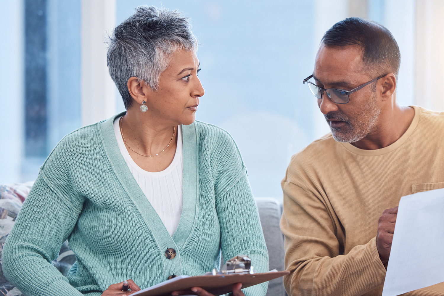 an older couple sits on a couch looking over a checklist