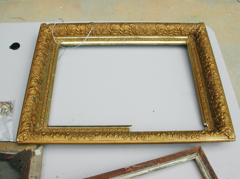 A wooden picture frame sits on a large level surface.