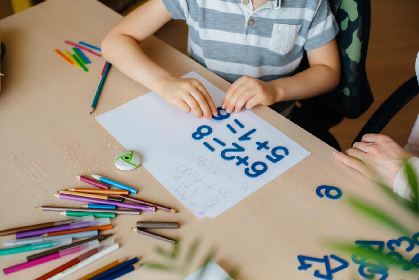 Child doing math homework on a table.