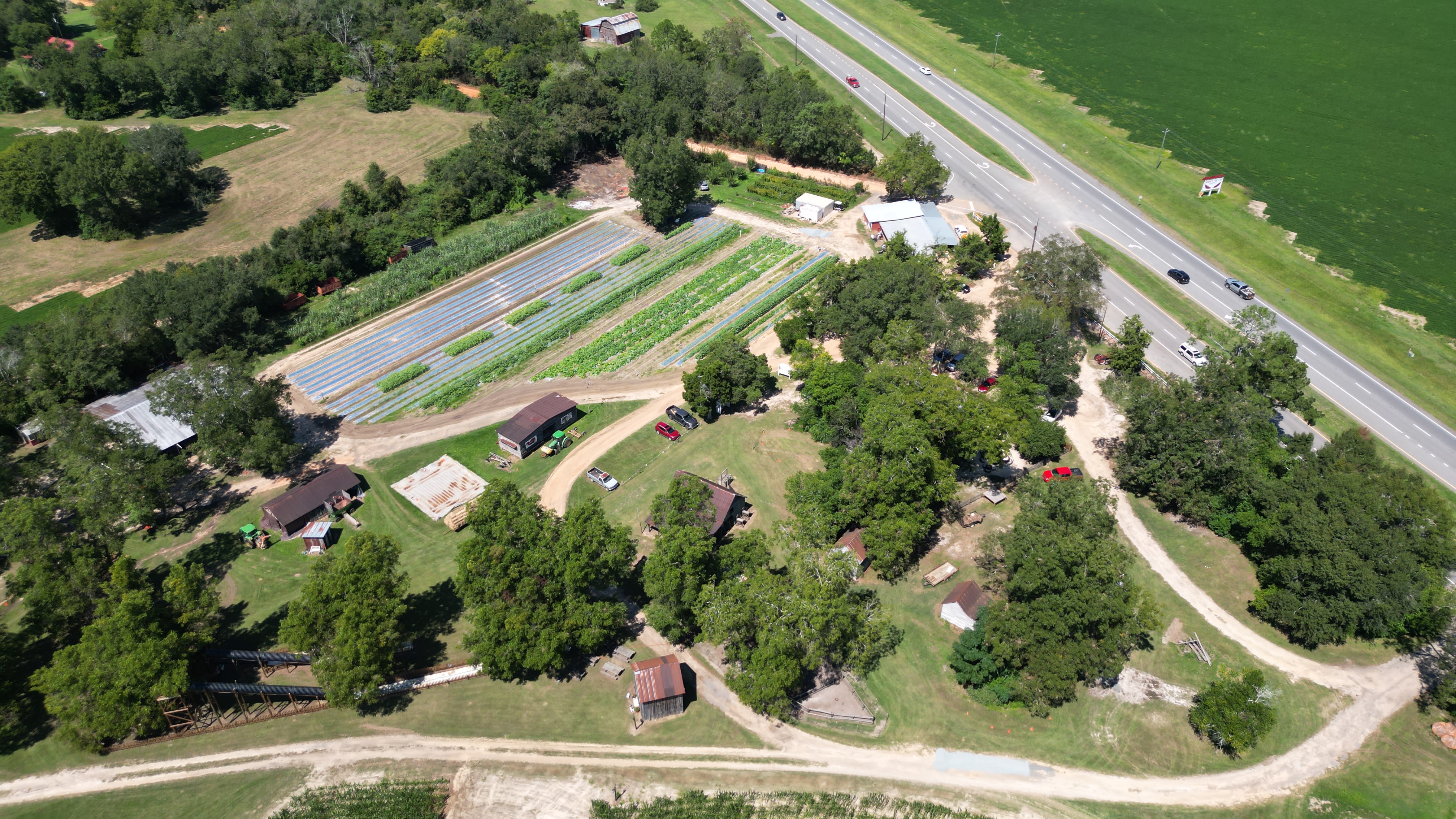 An aerial photo of the farm shows rows of crops, several buildings and trees. 