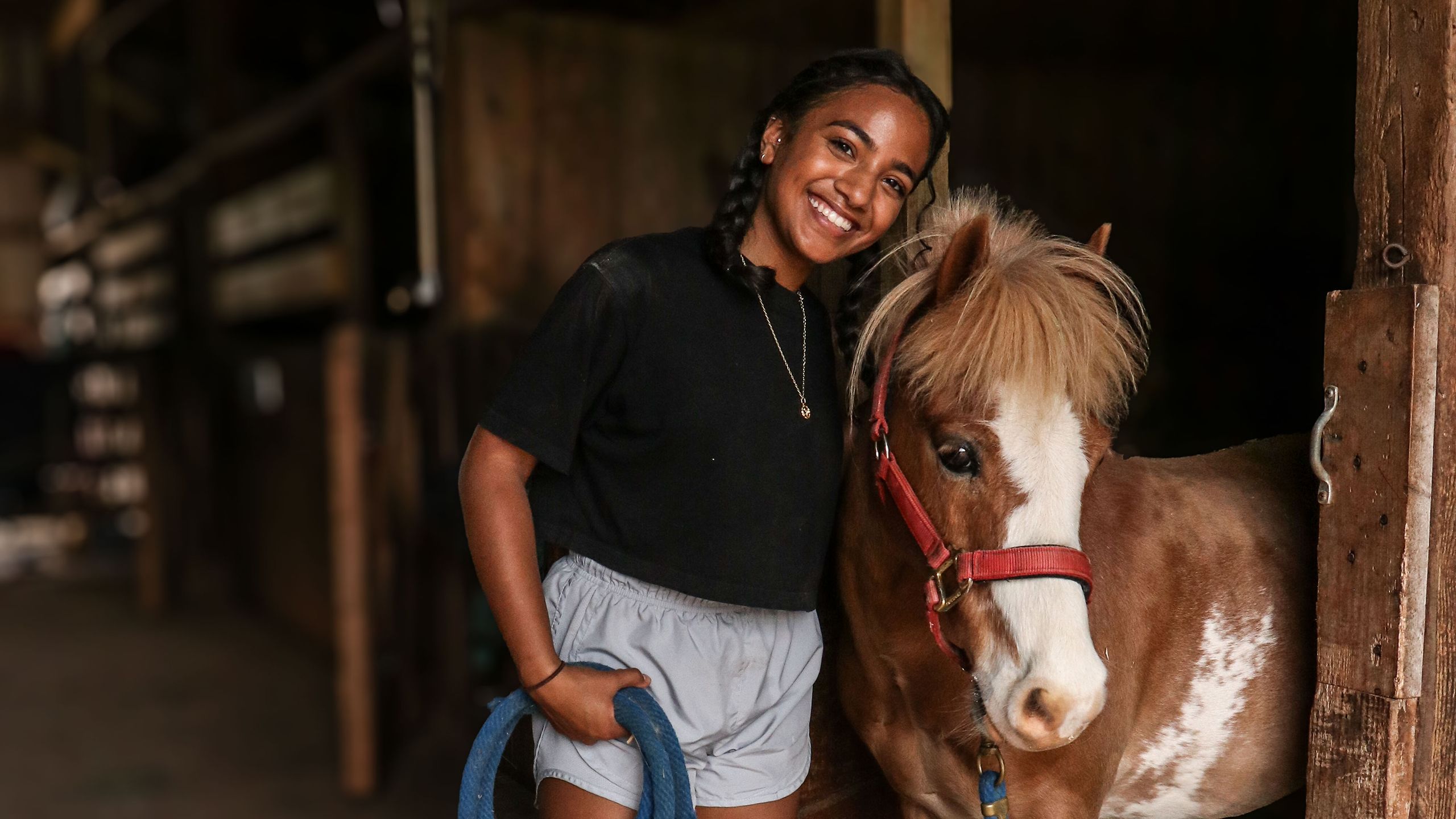 A girl poses next to a brown and white pony
