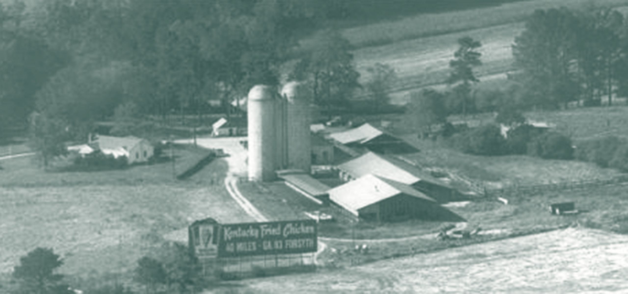 Farm with two silos and several shorter buildings with a KFC billboard outside