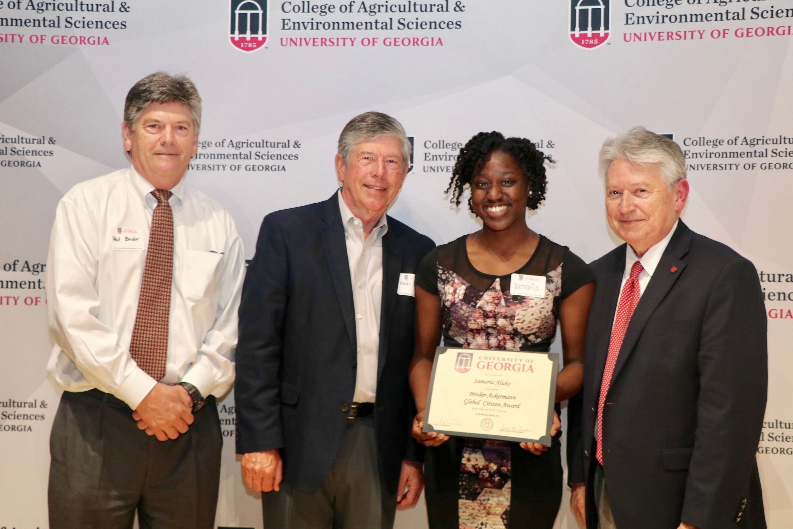 Samaria Aluko holding her global citizen award certificate while standing with Patrick, Hans, and Joe Broder