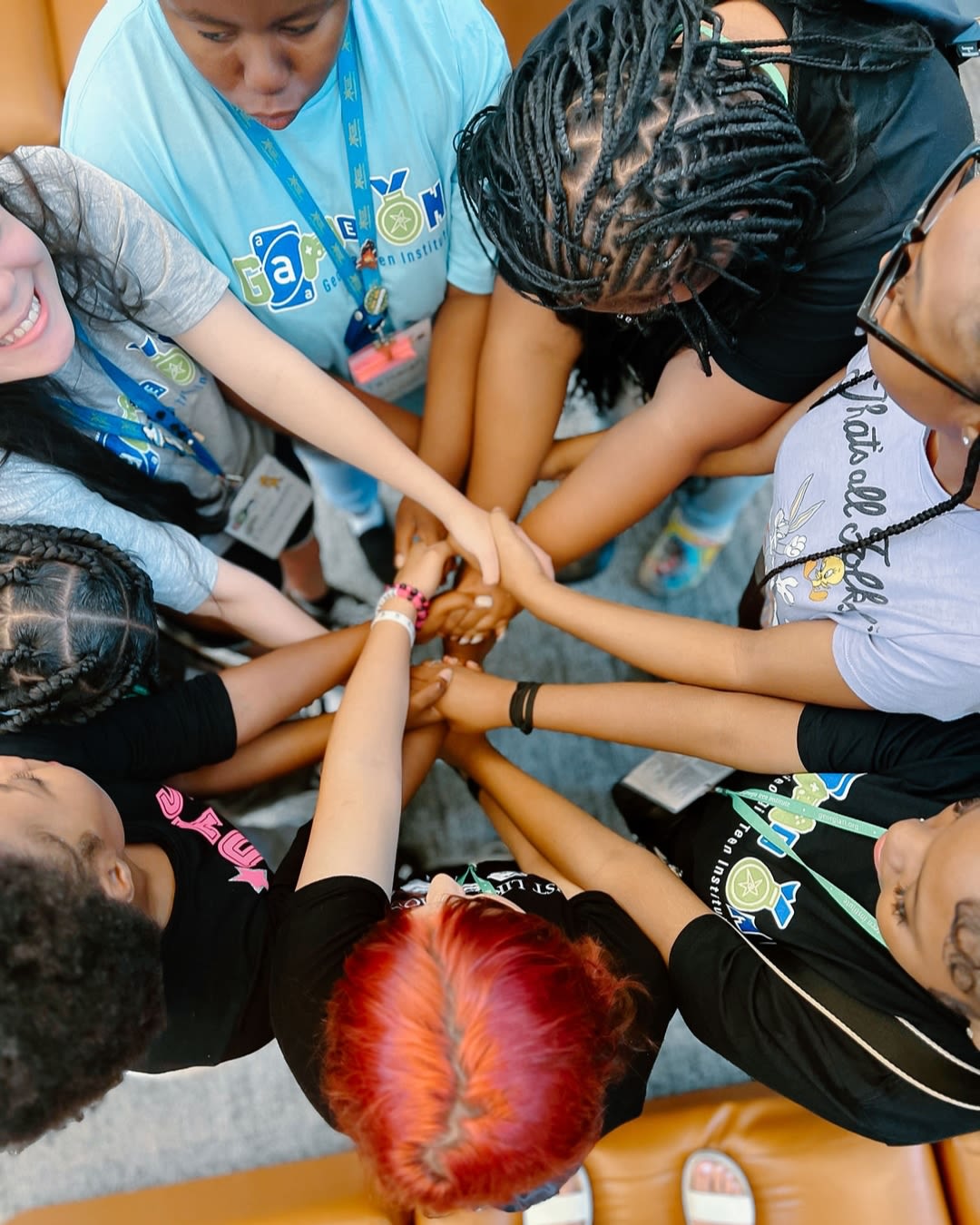 A closeup of several hands joined together in the middle of a circle of people
