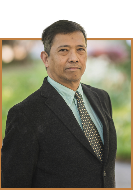 A headshot of Cesar Escalante in a suit and tie against a blurring green background