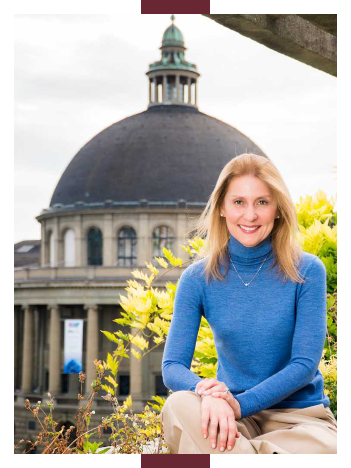 Consuelo De Moraes sits with her hands on one knee with a large domed building in the background