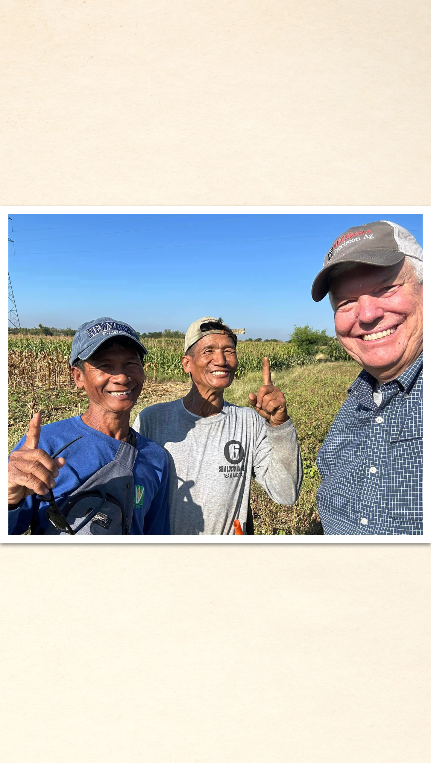 Ben Kemerait, Benjamin Tabur and Eduardo Tabur stand in a cornfield, each raising their pointer fingers signing number 1