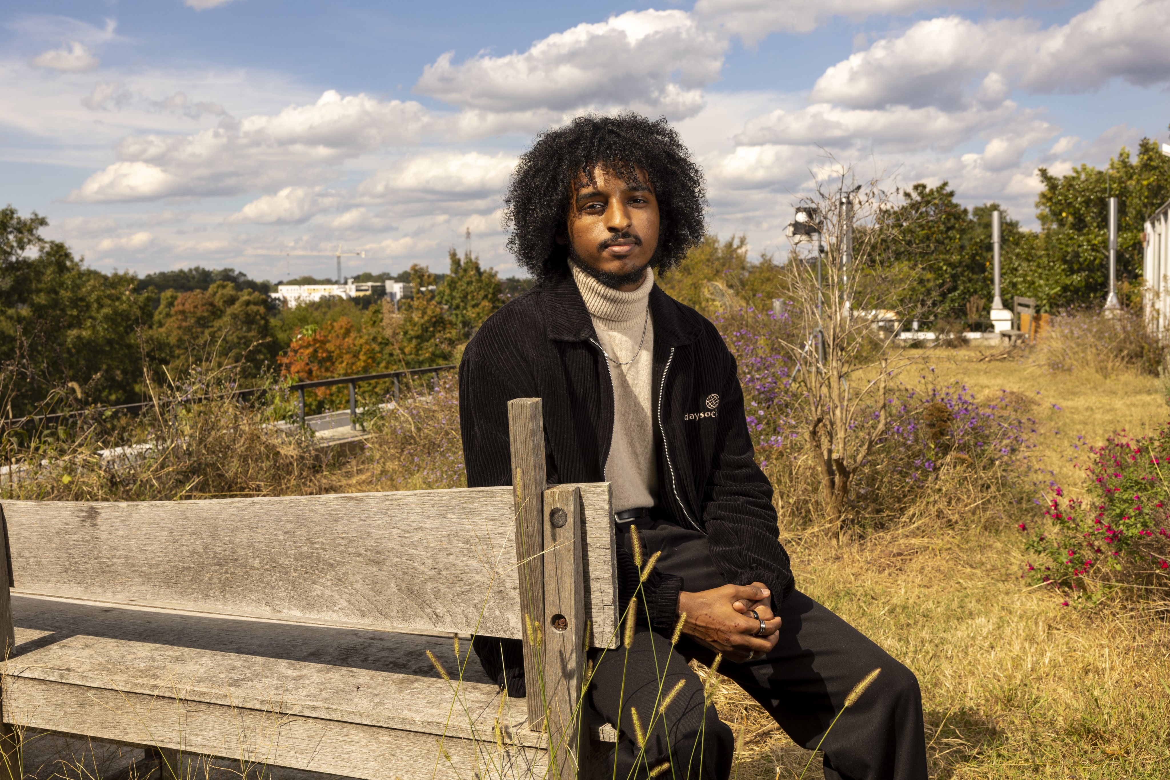 Nathan Tesfayi sitting on a bench in a field.