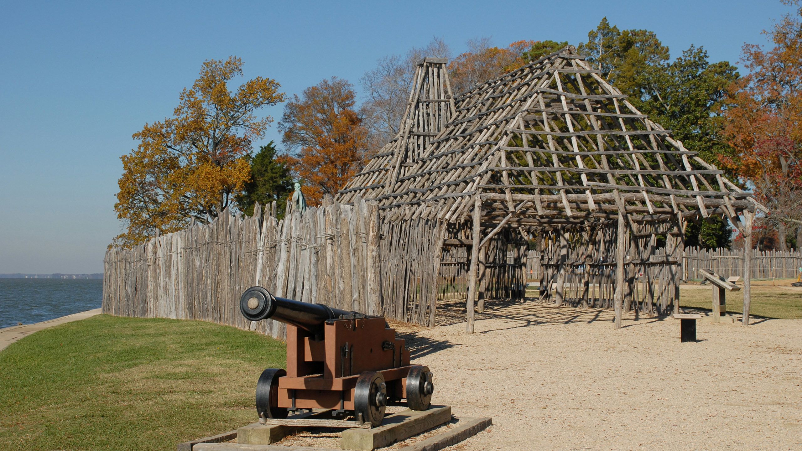 A structure built out of wooden logs with a cannon in the foreground and a forest scene in the background