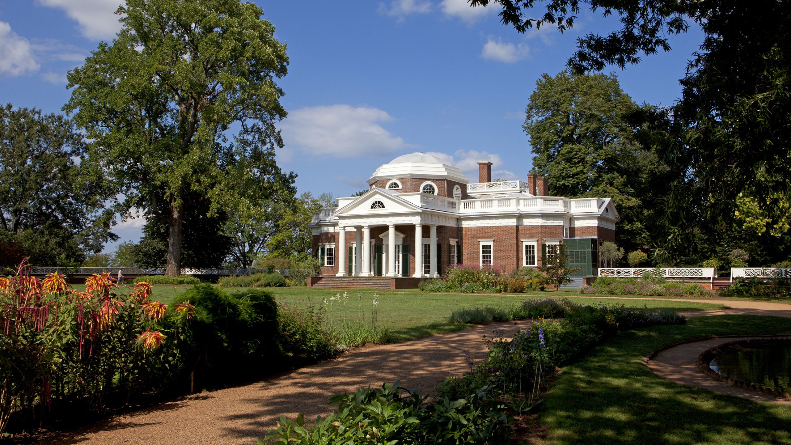 Monticello, a large brick building with white trim and white pillars, standing in a lush landscape
