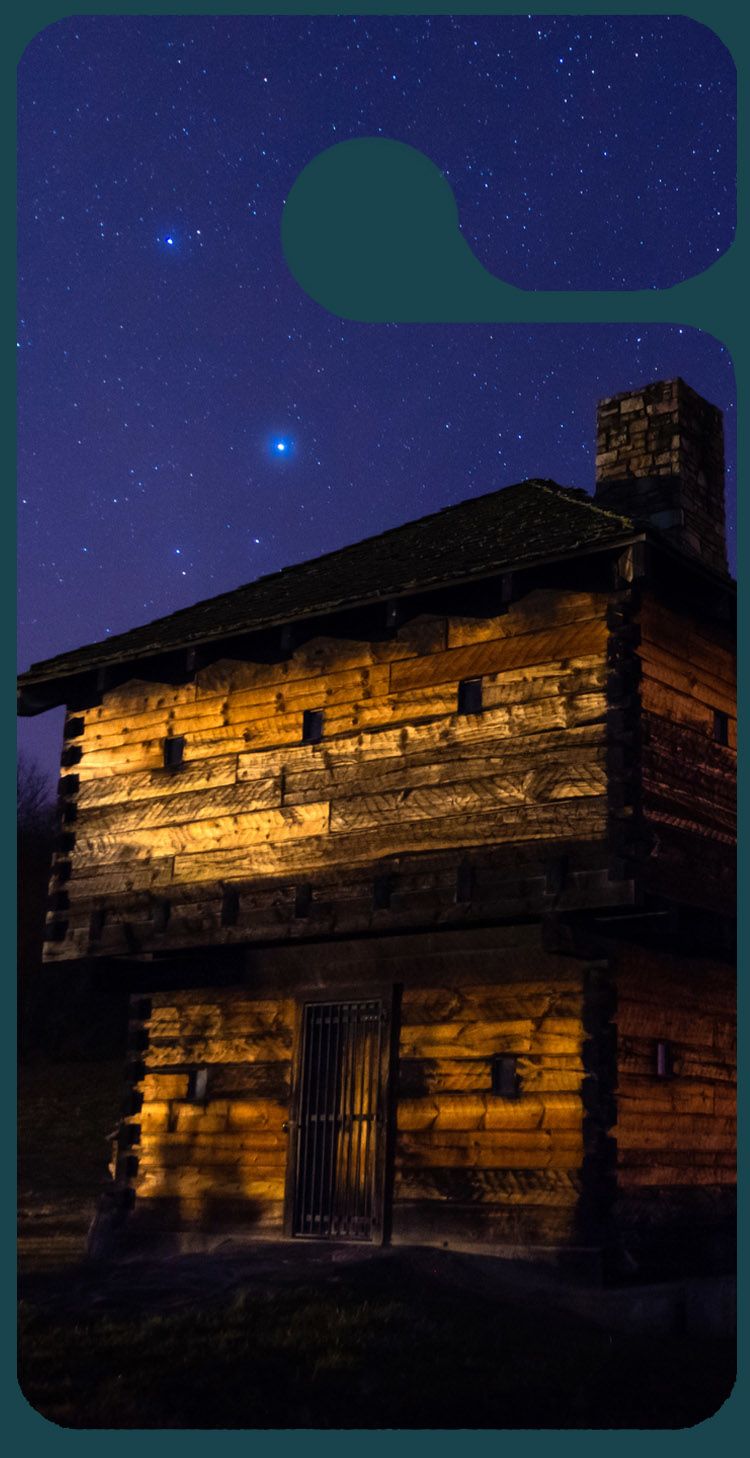 A graphic of a car tag displaying a night scene with an illuminated wooden house