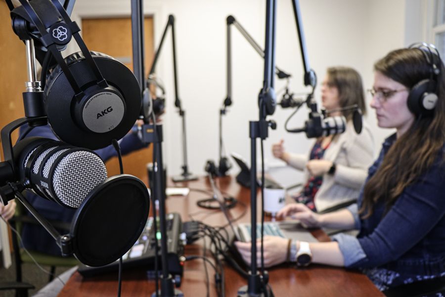 Podcasting studio showing microphones and headphones, with Cultivating Curiosity hosts Jordan Powers and Emily Davenport in the background.