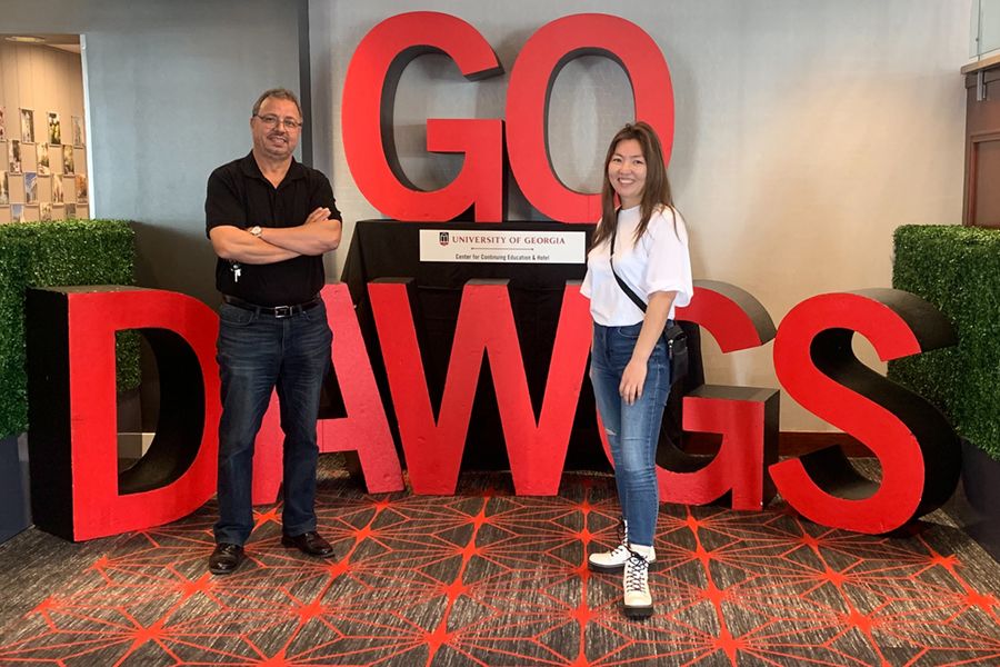 UGA Professor Mohamed Mergoum and Borlaug Scholar Urtnasan Ganbaatar pose in front of a GO DAWGS display on the UGA Athens campus.