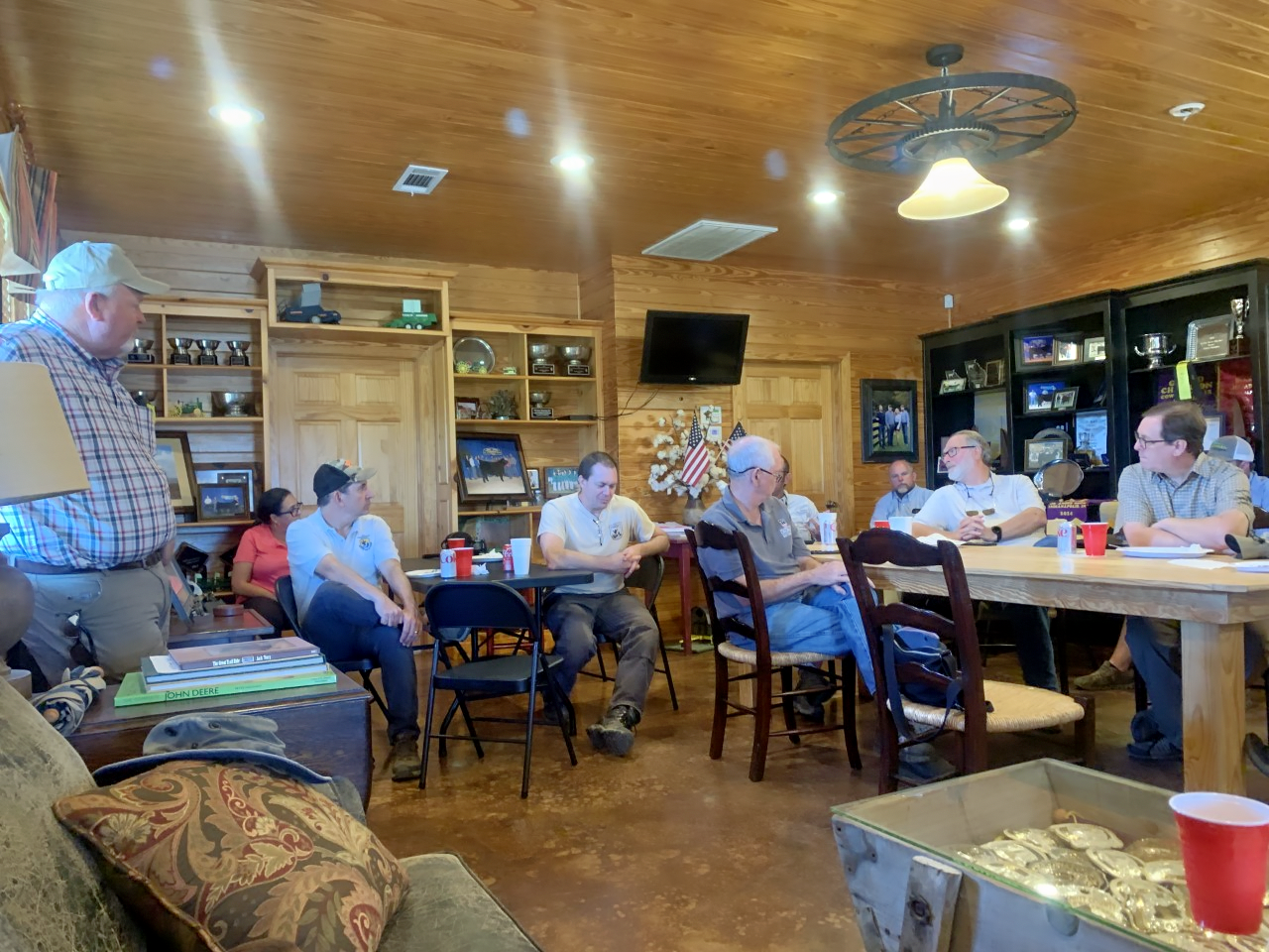 A group of people sit in a kitchen talking to one another and with farmer, Bart Davis. 