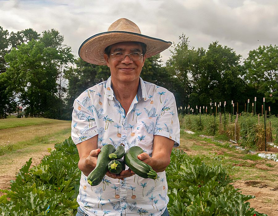 Juan Carlos Díaz-Pérez stands in a field showing off ripe zucchini.