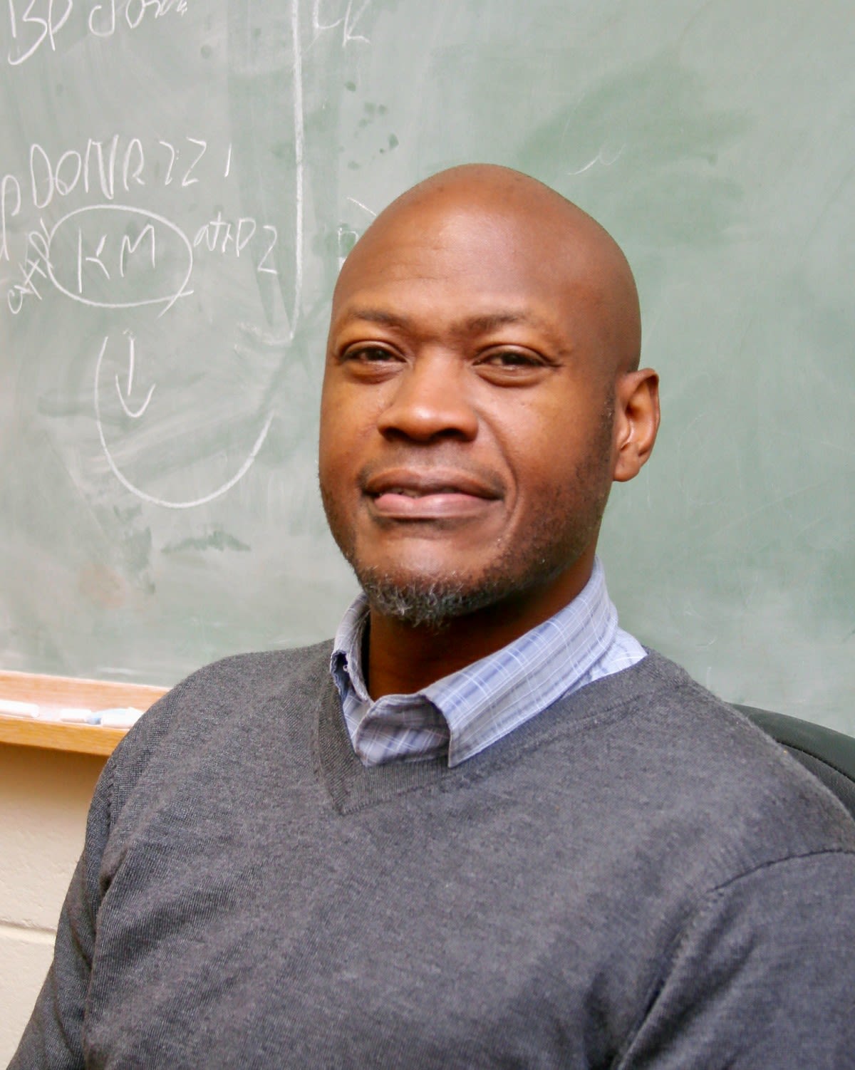 Walcott sits in front of a chalkboard in the classroom