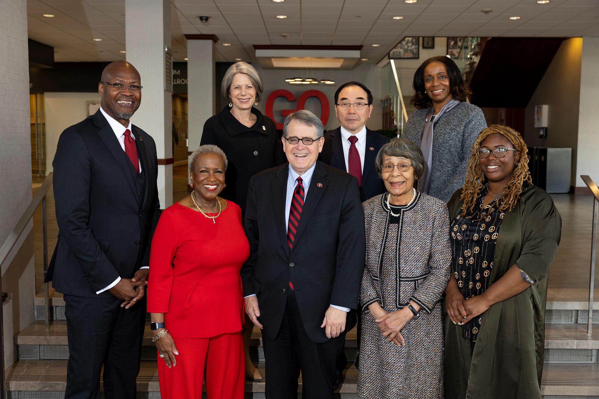A group of eight gather in the Georgia Center lobby in professional attire