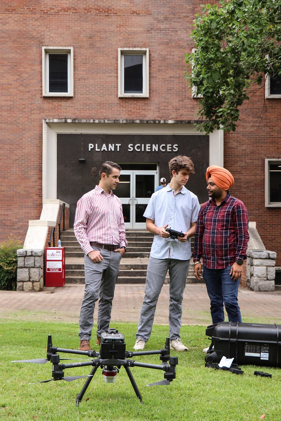 Leonardo Bastos, Clayton Bivins, and Amrinder Jakhar stand outside the UGA Plant Sciences building with a drone