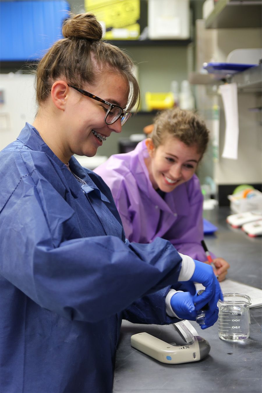 Olivia Hawkins and Anna Townsend open a chemical sample in a lab.