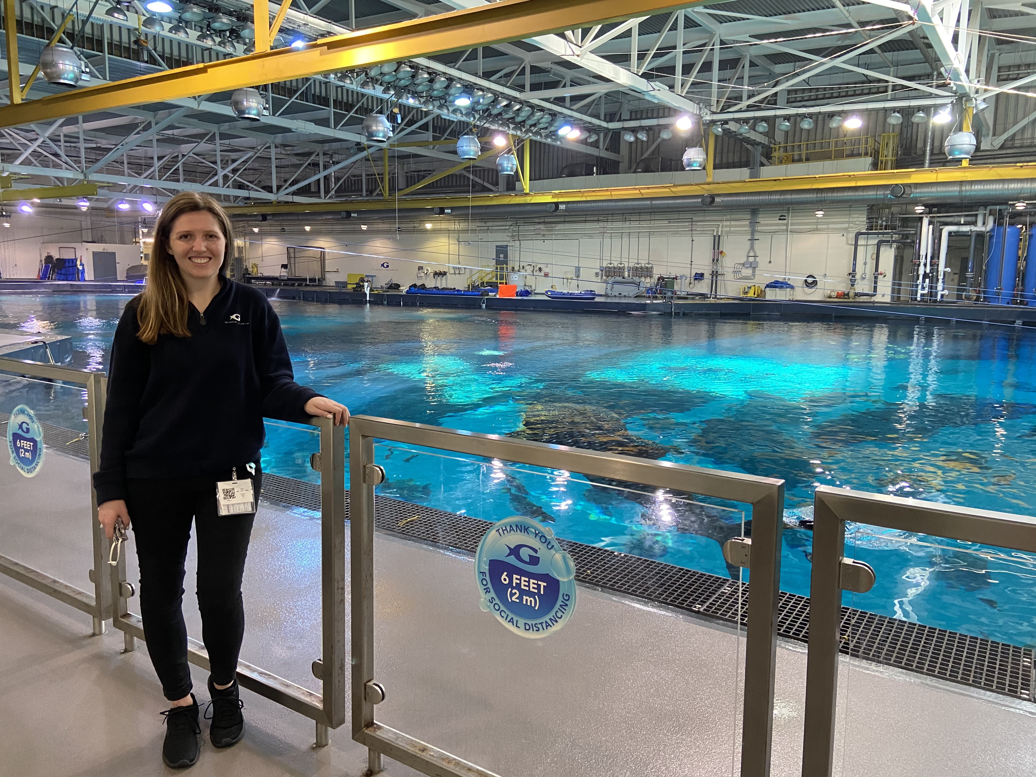 Siraguga volunteers at the Georgia Aquarium, where she stands next to a large pool