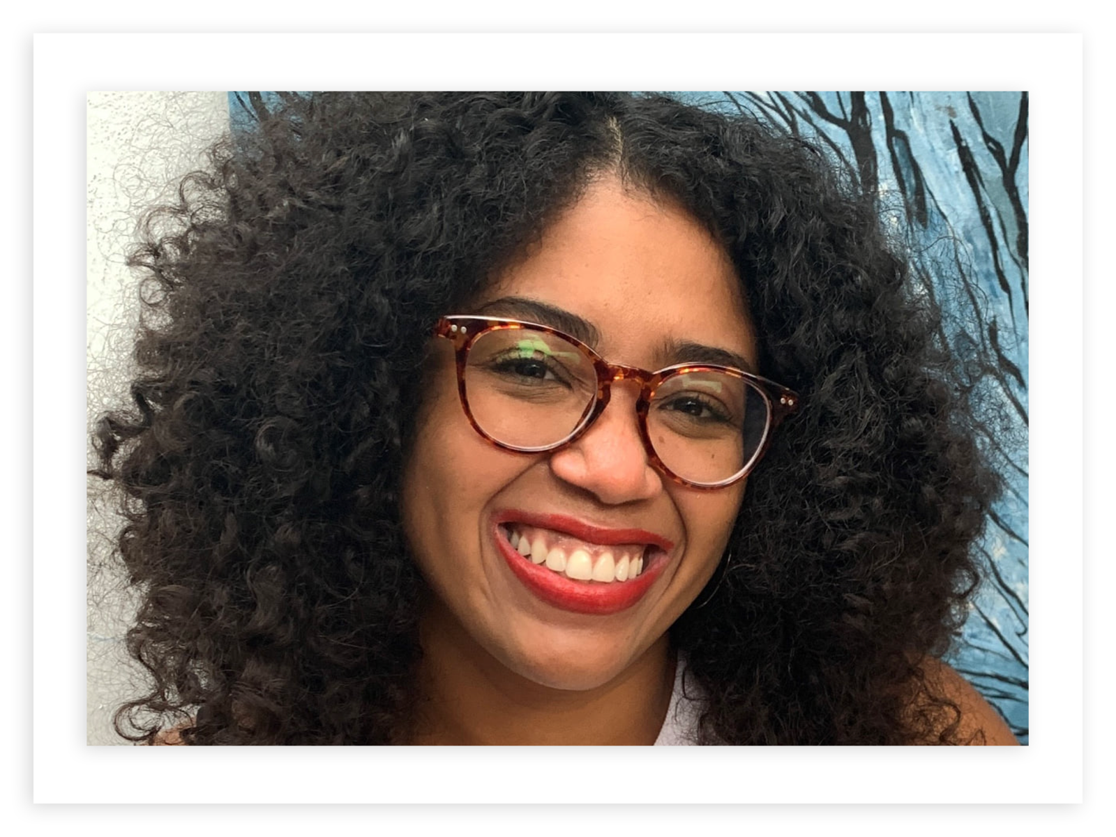 Anna Williams, wearing tortoiseshell glasses smiles broadly