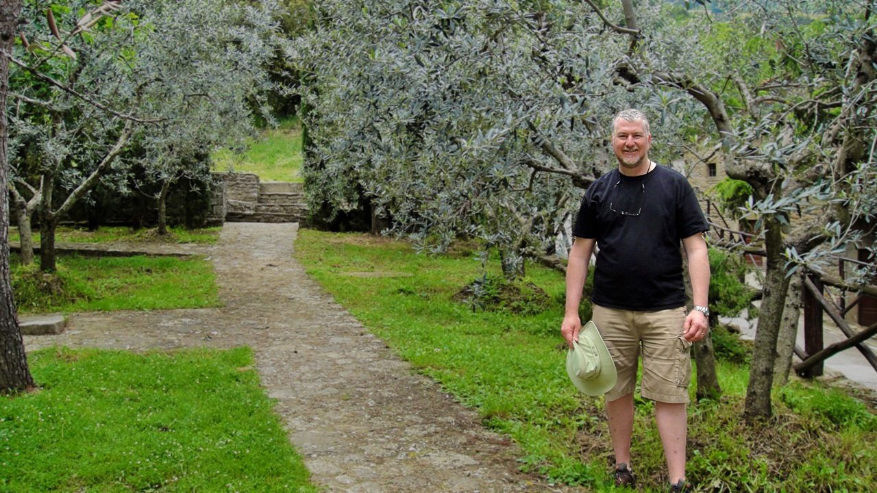 Phil Brannen smiles while standing in an orchard
