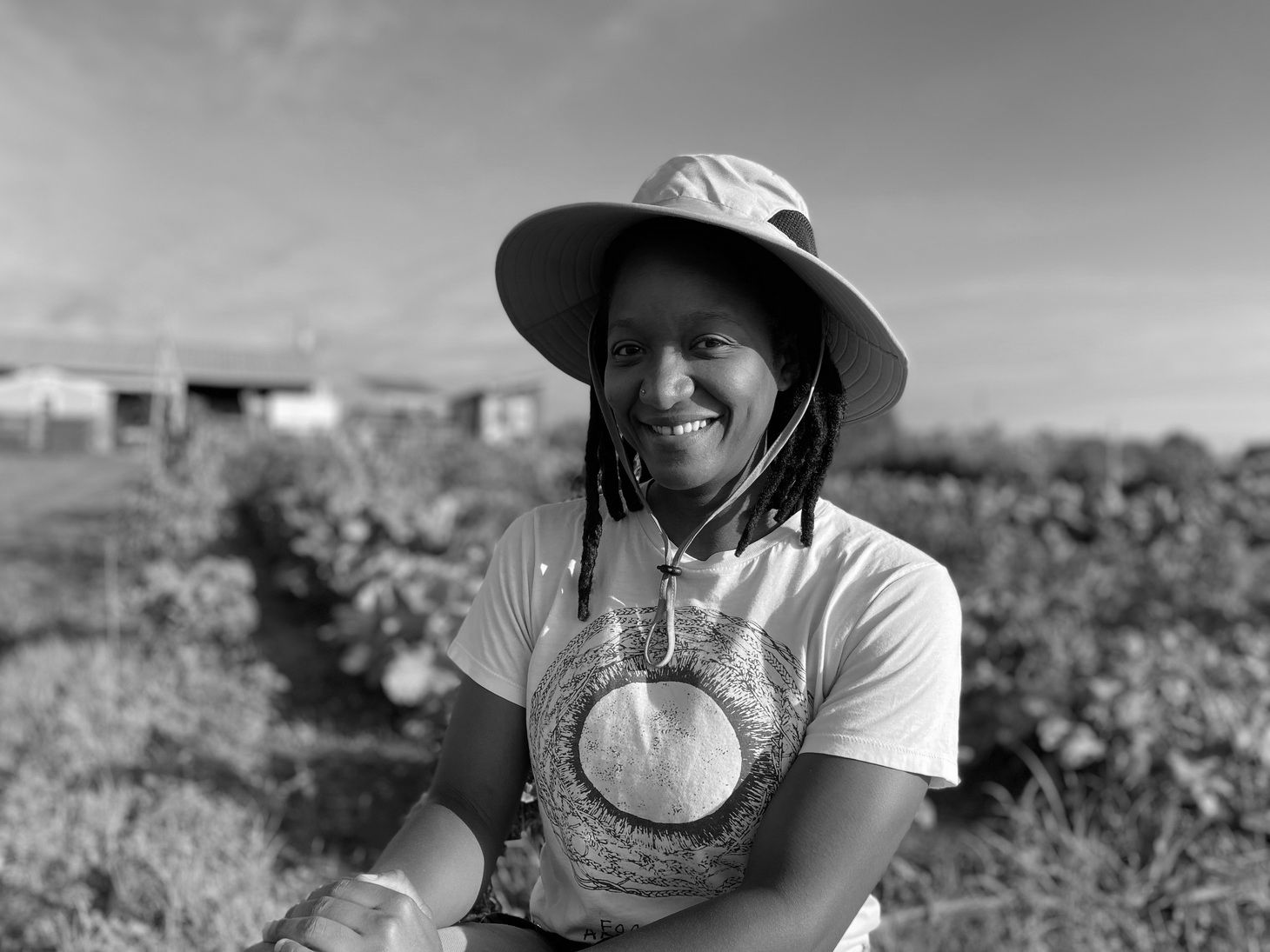 Patty Lacrete smiles in front of a garden plot at UGArden (photo in black and white))