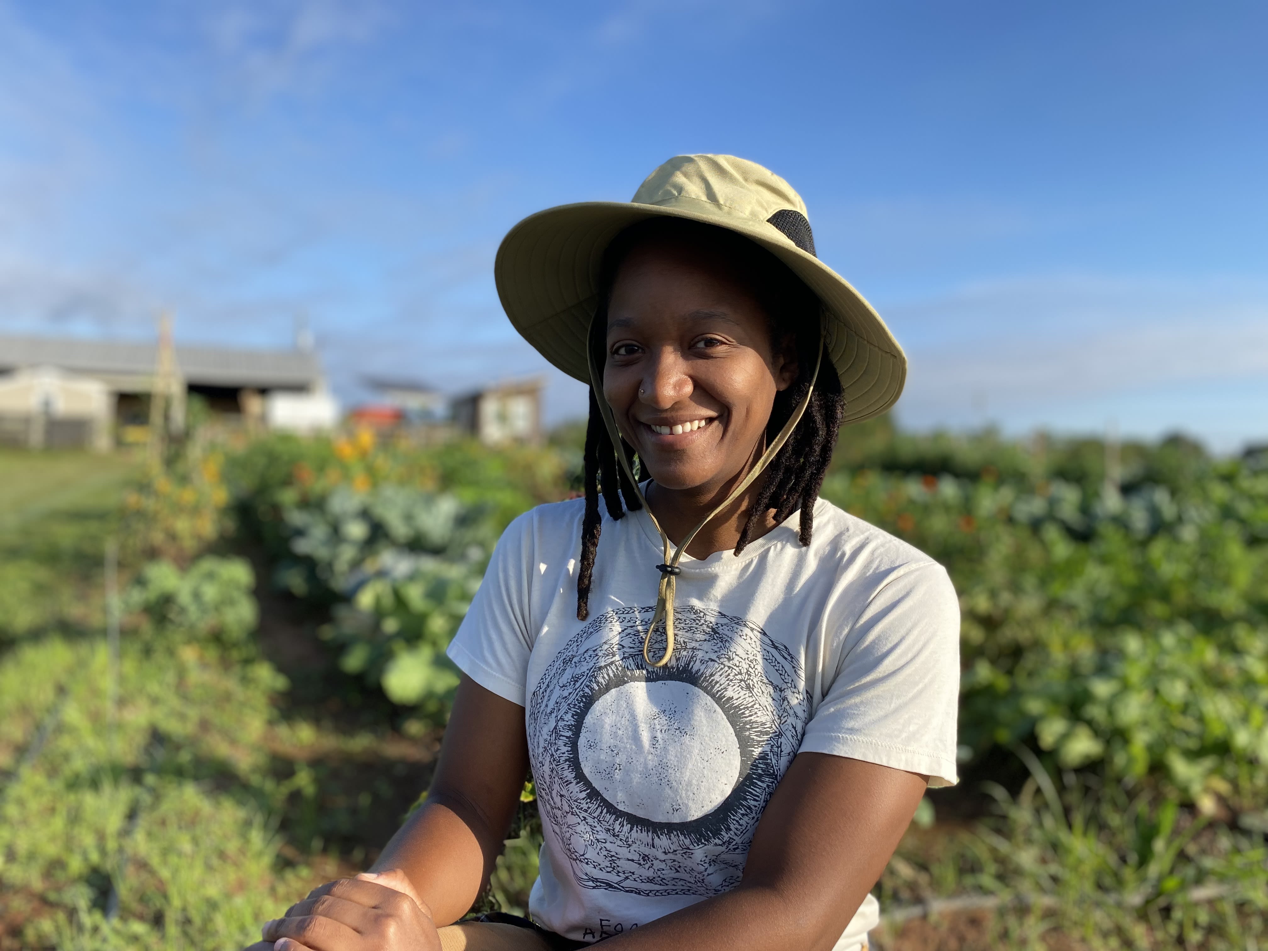 Patty Lacrete smiles in front of a garden plot at UGArden (photo in full color)
