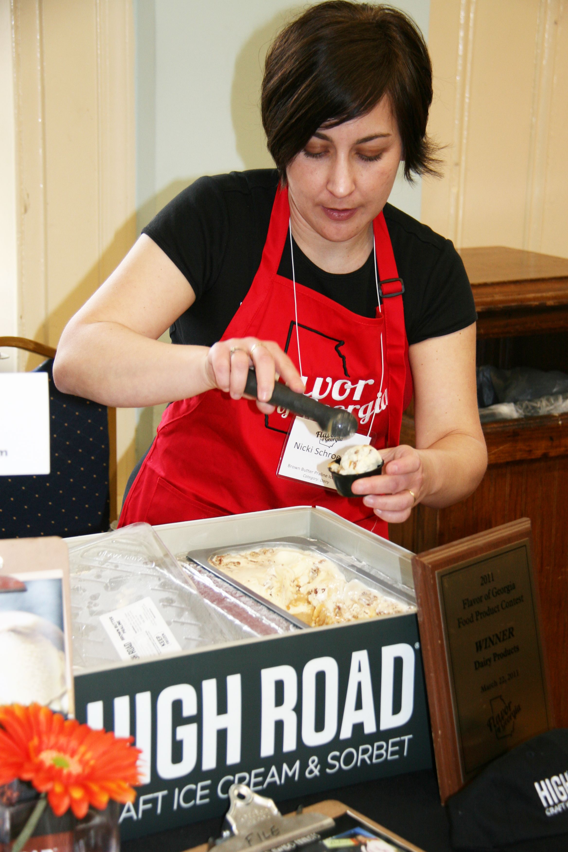Co-founder scoops ice cream while wearing an apron.