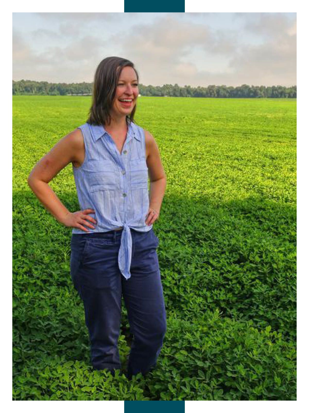 Joyous woman standing in a peanut field, looking off camera with her hands on her hips.
