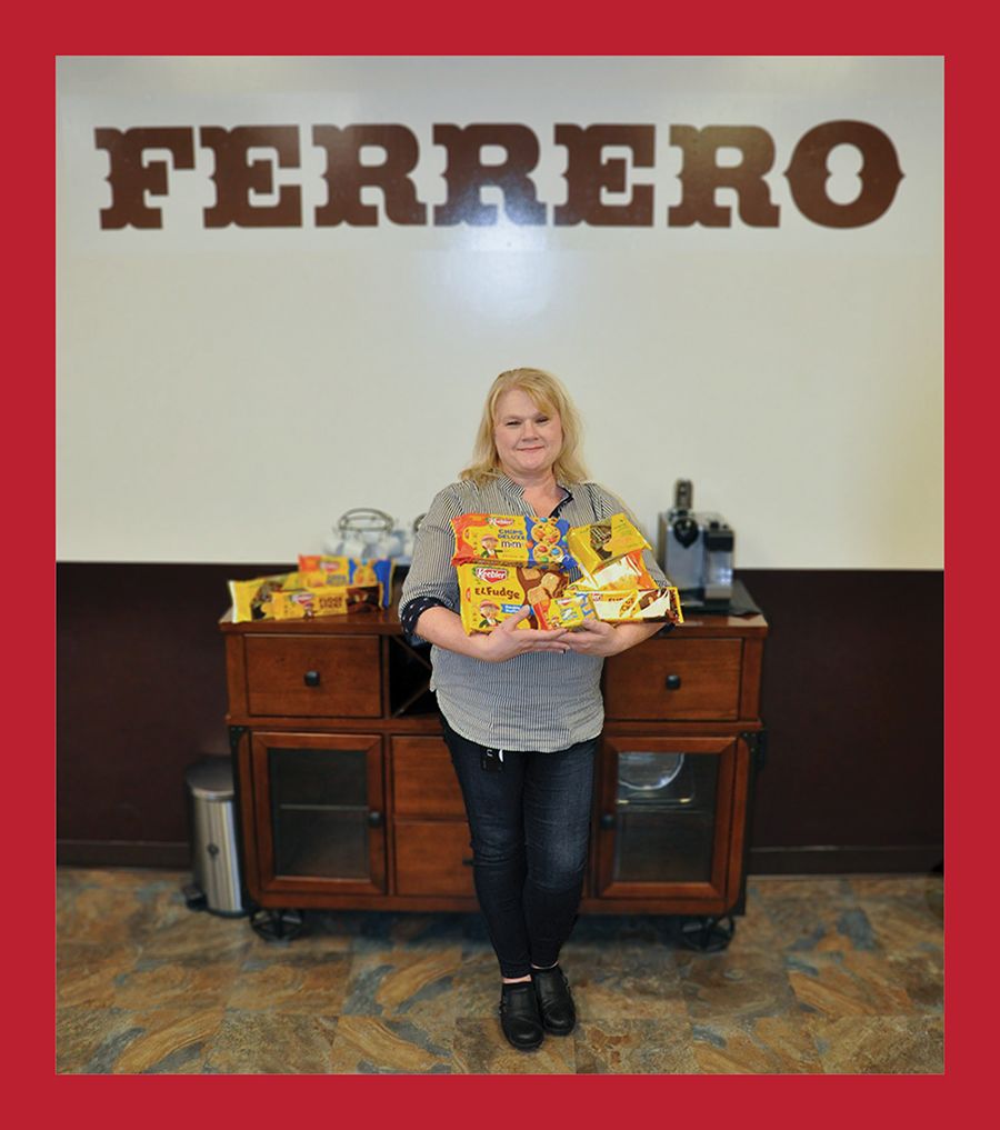 Dupree stands in front of a Ferrero sign holding packages of cookies