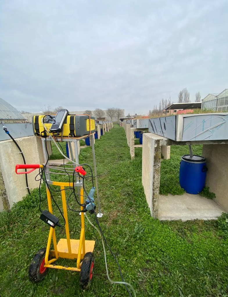 A yellow instrument on wheels is used to measure greenhouse gases in an aisle of mesocosms