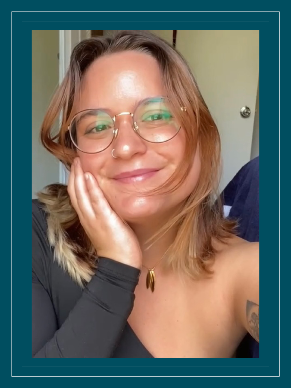 Lugo-Arroyo smiles and takes a selfie while wearing a one-shoulder top and glasses