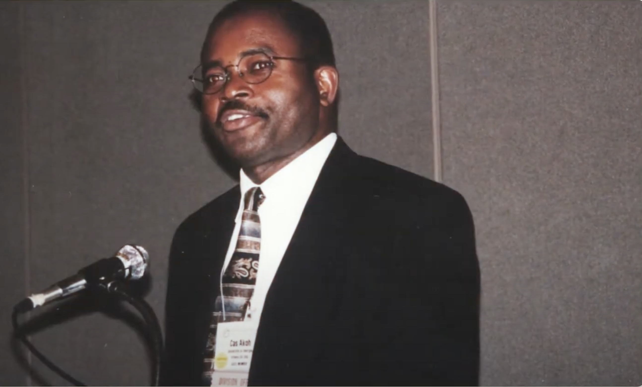 Akoh leans against a chair in a studio portrait