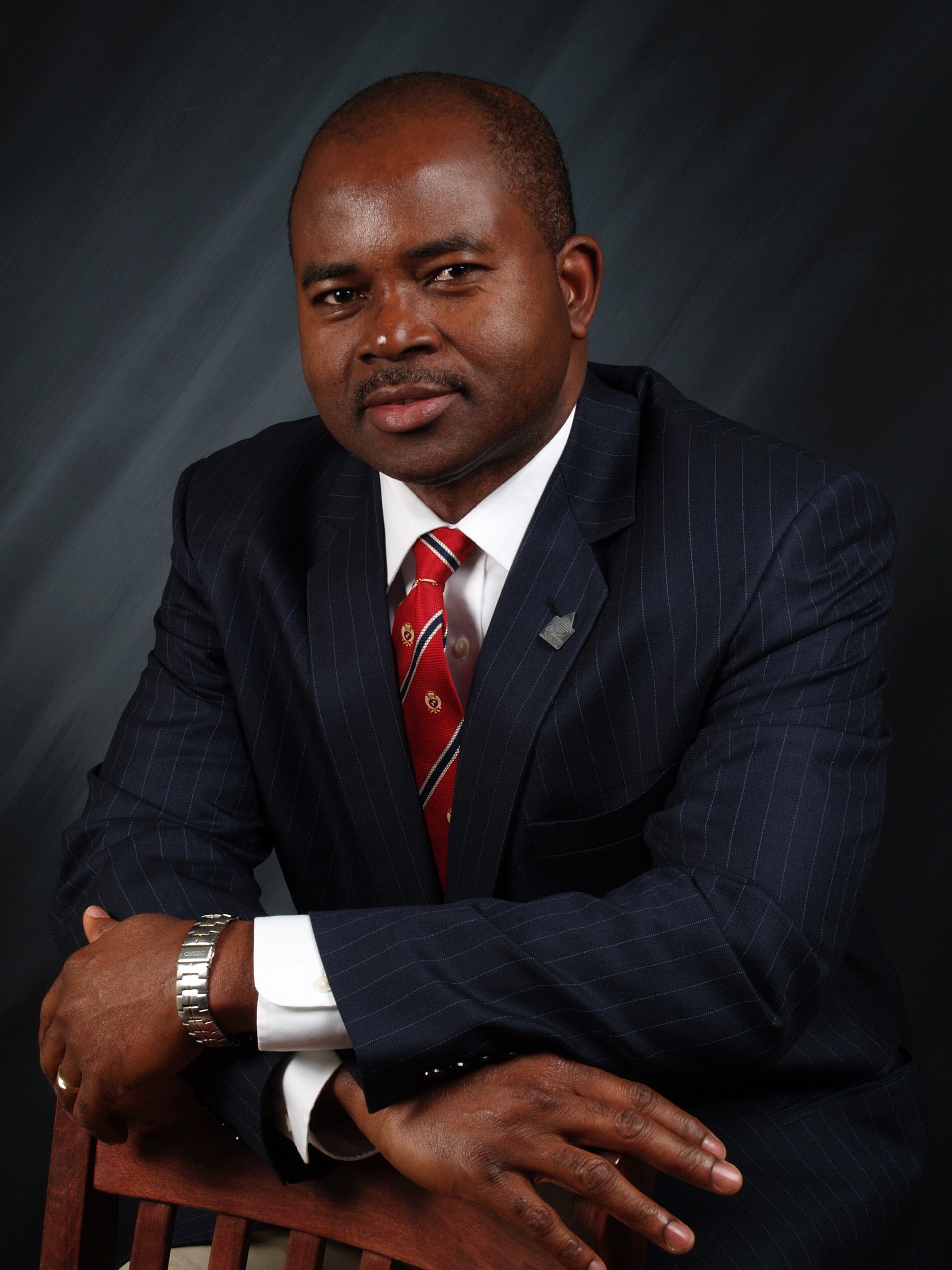 Akoh leans against a chair in a studio portrait