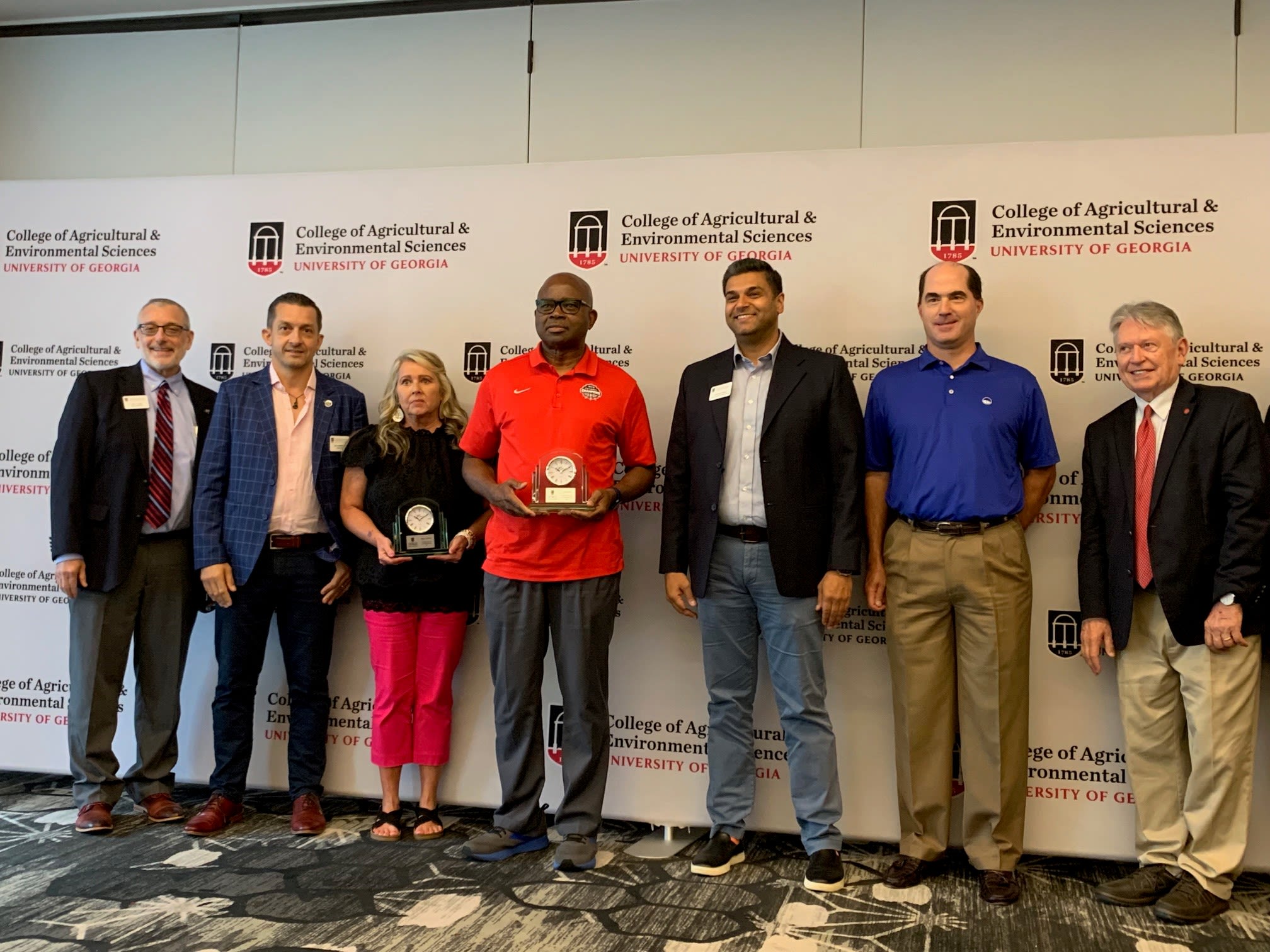 Akoh poses with other award recipients in front of a CAES backdrop