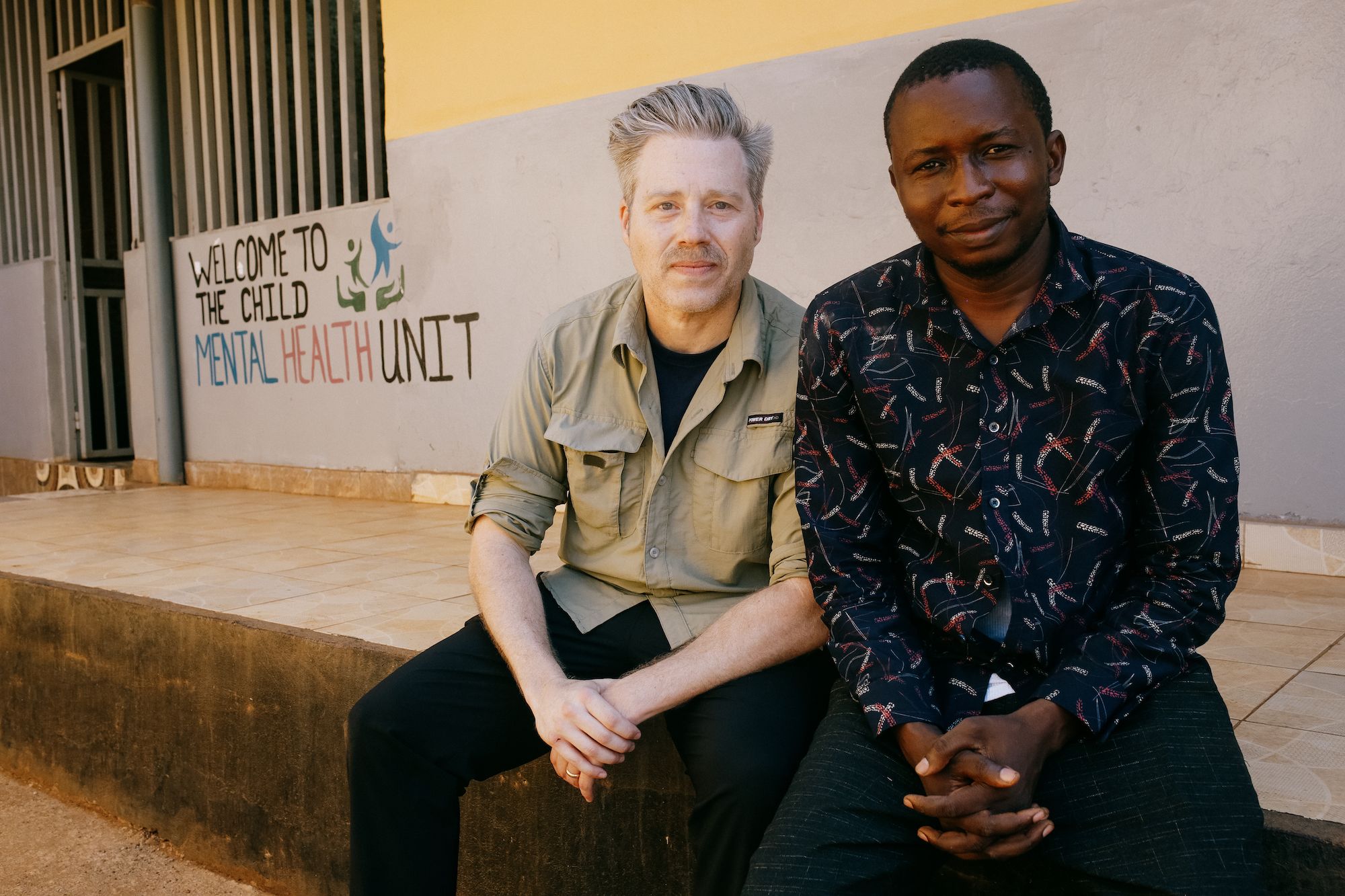 Hall and Mansaray sit on a stoop outside of a hospital