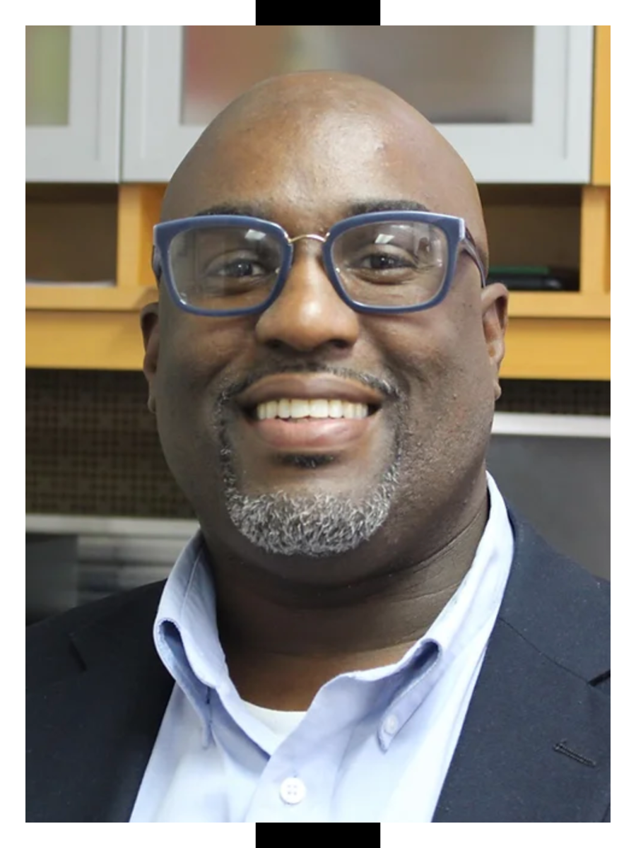 James Scott smiles in a blue suit and glasses
