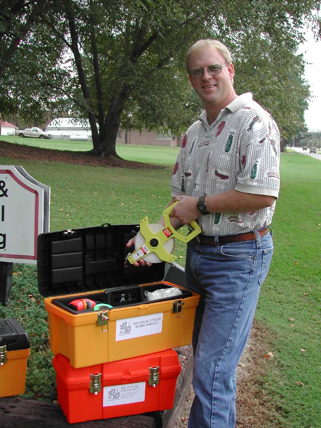 Hawkins opens up an Adopt-A-Stream Visual Stream Monitoring Kit, which is housed in a toolbox outdoors.