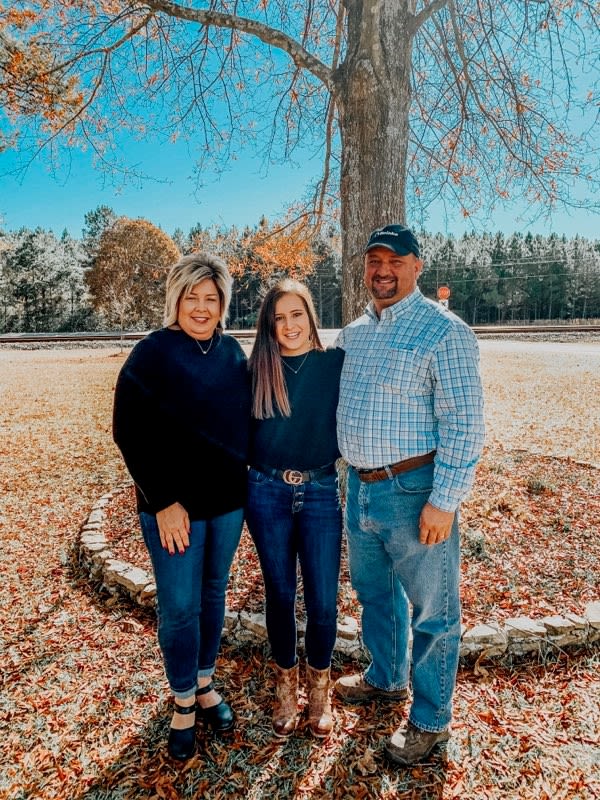 Hall (far right) stands with his family in an outdoor setting during fall