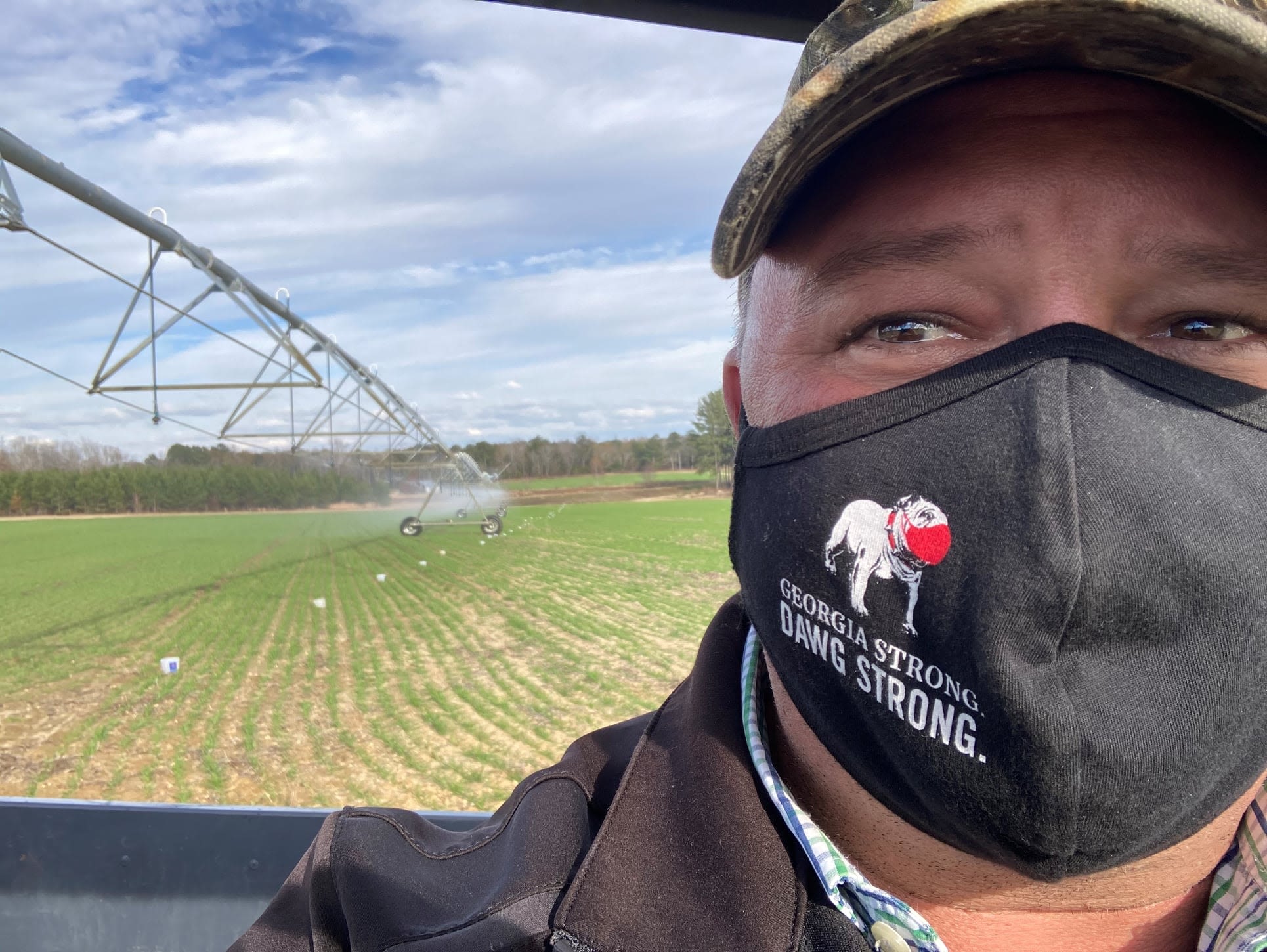 Hall conducts a mobile irrigation lab, or MIL, in a Bleckley County farmer's field. He is masked and taking a selfie in front of the irrigation system.